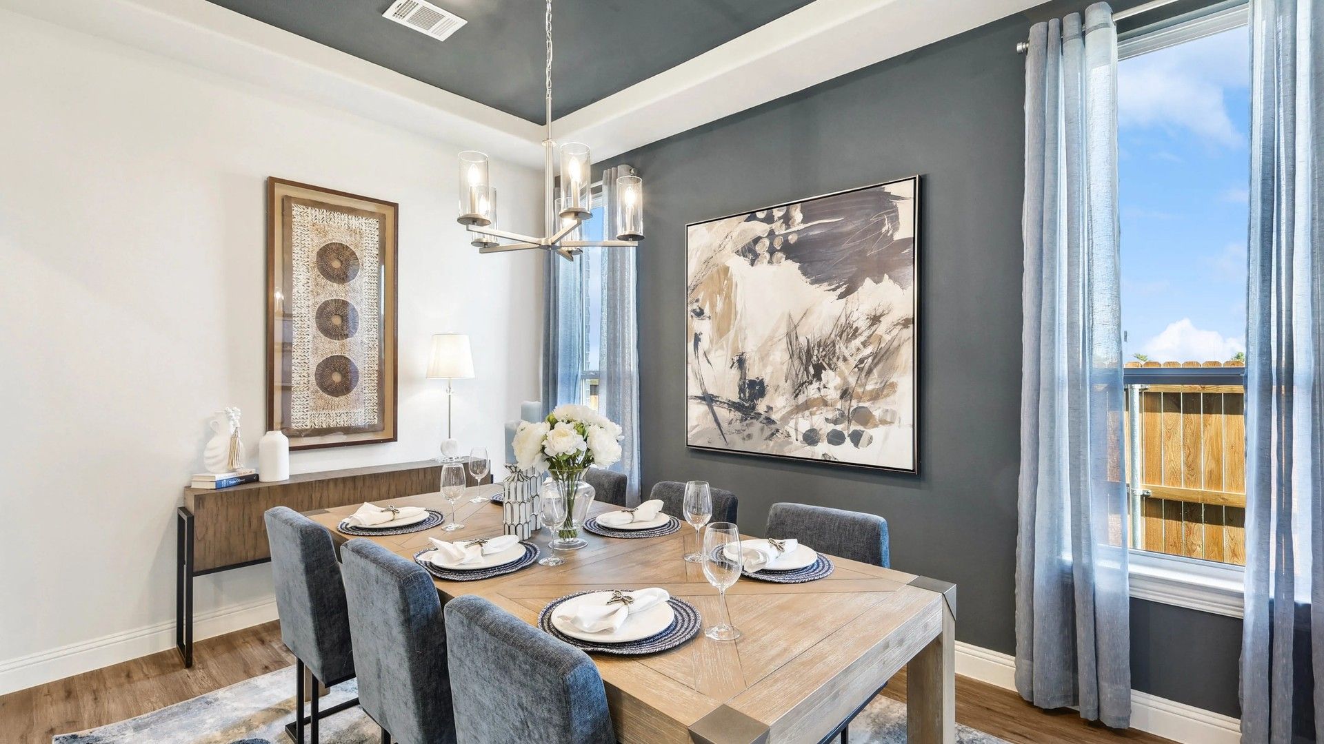Ridge Crossing's dining room features sleek velvet chairs and a wooden table beneath a modern chandelier.