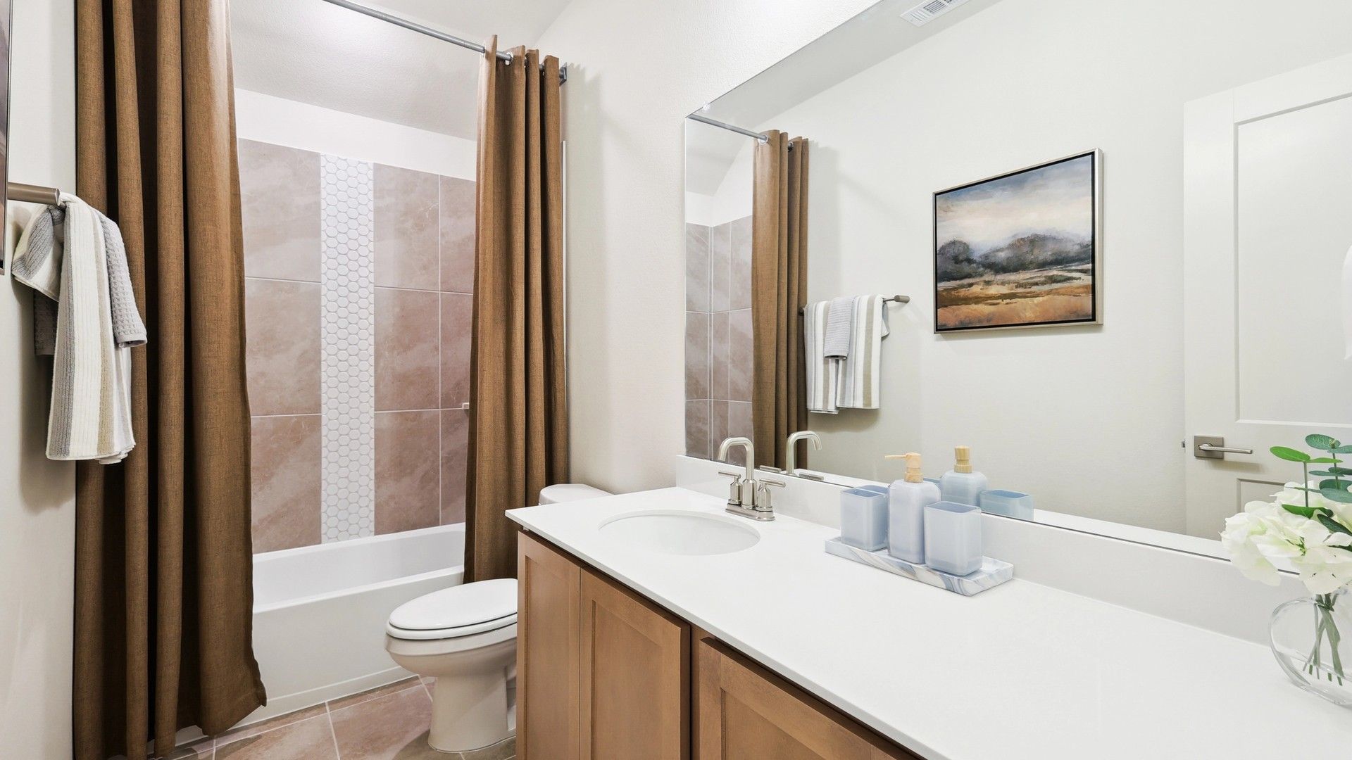 Elegant bathroom showcases a wood vanity and exquisite tile work in The Oaks community.
