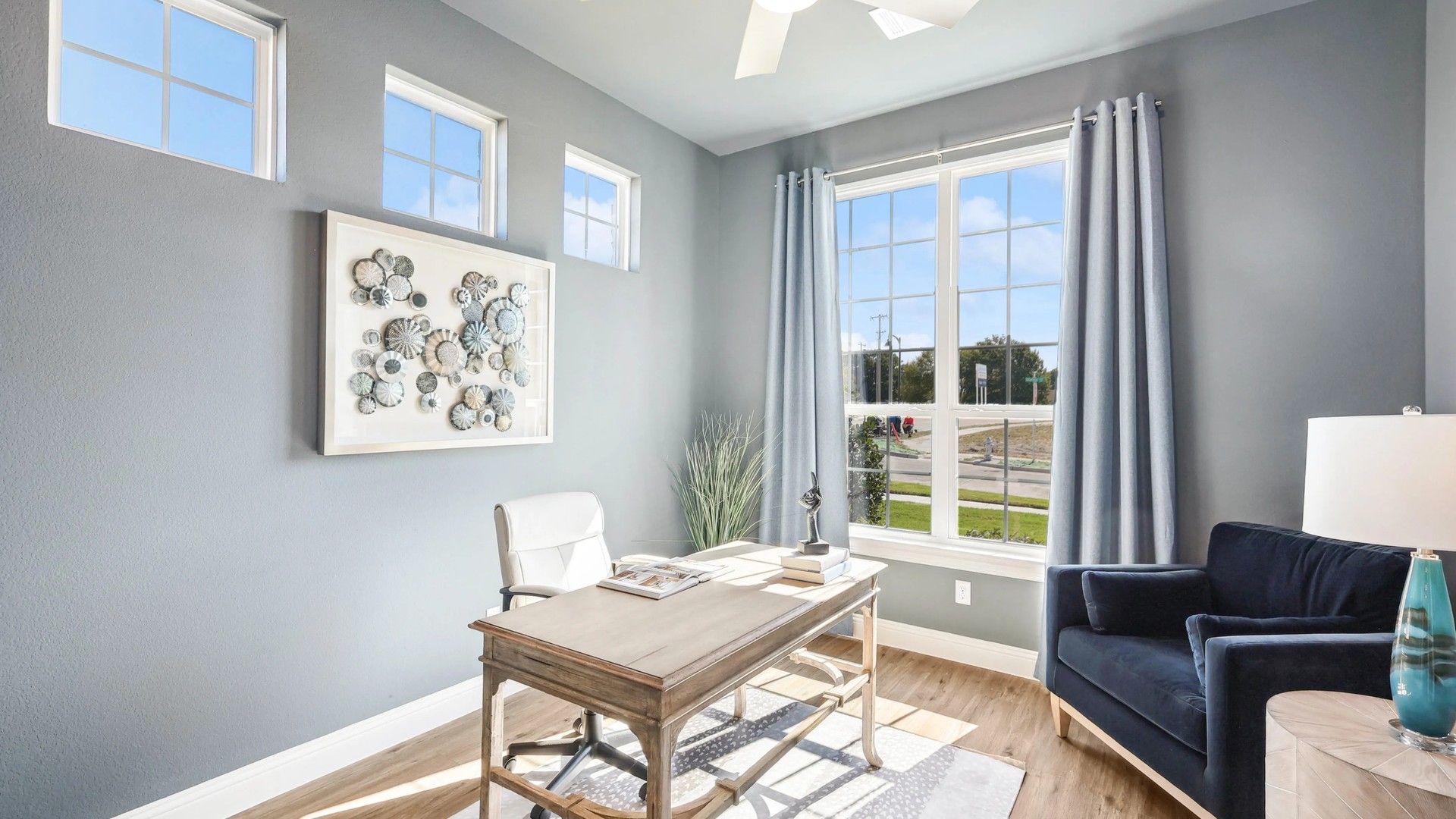 Luxurious office features expansive windows, sleek ceiling fan, and sophisticated decor in Ridge Crossing.