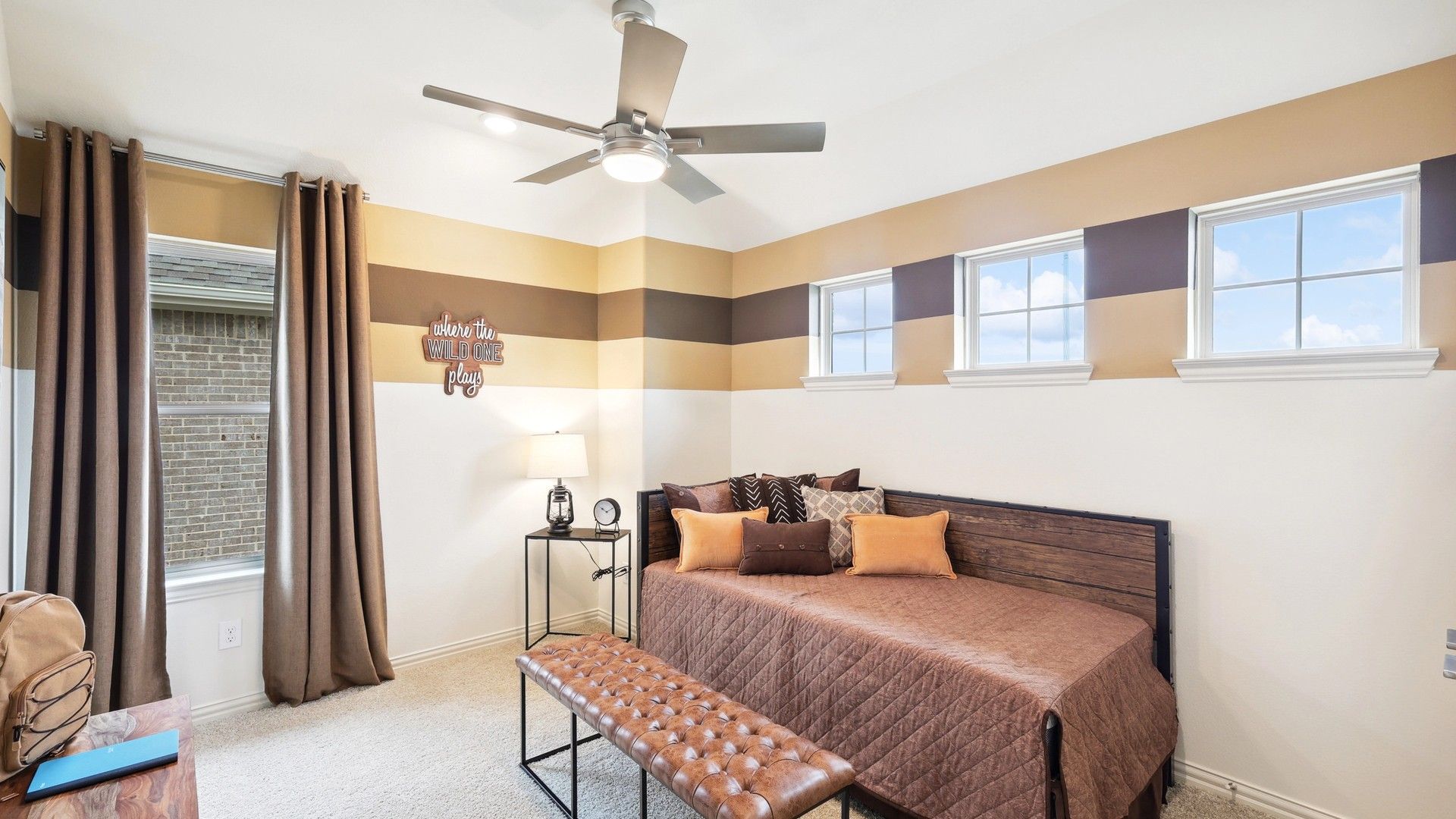 Experience luxury with striped accent walls and sleek ceiling fan in The Oaks community.