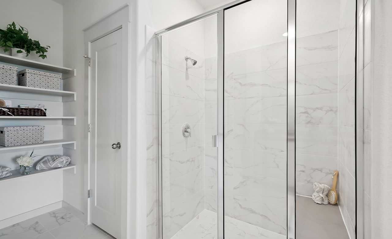 Luxurious glass panel shower and marble tiles define this Walden Pond bathroom's modern elegance.