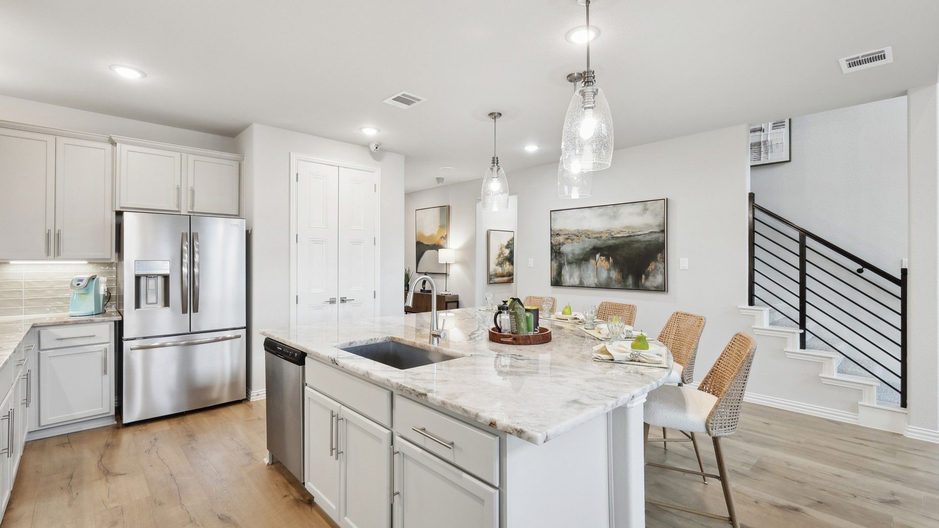 Sophisticated marble island and sleek lighting elevate this Wildflower Ranch kitchen.