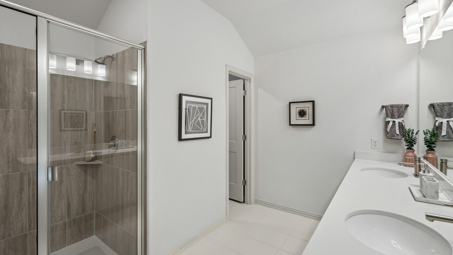 Elegant frameless glass shower and dual sinks enhance this Bel Air Village bathroom's refined sophistication.