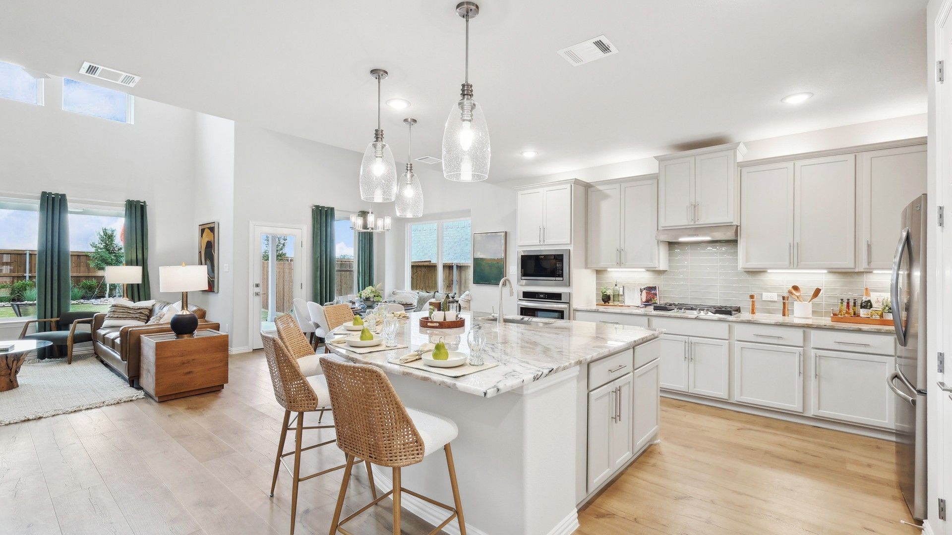 Luxurious marble island and sleek light fixtures elevate this Wildflower Ranch kitchen's elegance.