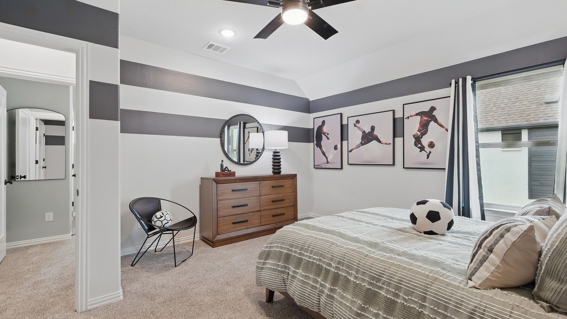 Sophisticated bedroom with striped walls, fine wood dresser, and chic sports accents in Westridge. Luxurious yet playful.