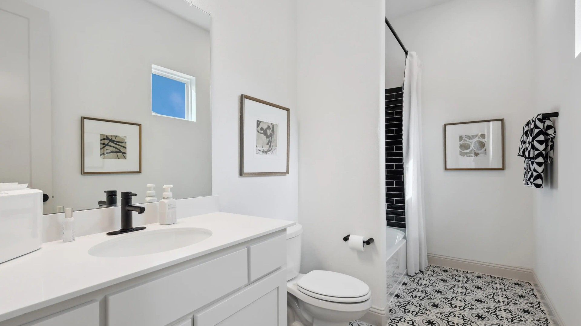Elegant bathroom boasts handcrafted black fixtures, striking patterned tile, in Westside Preserve.