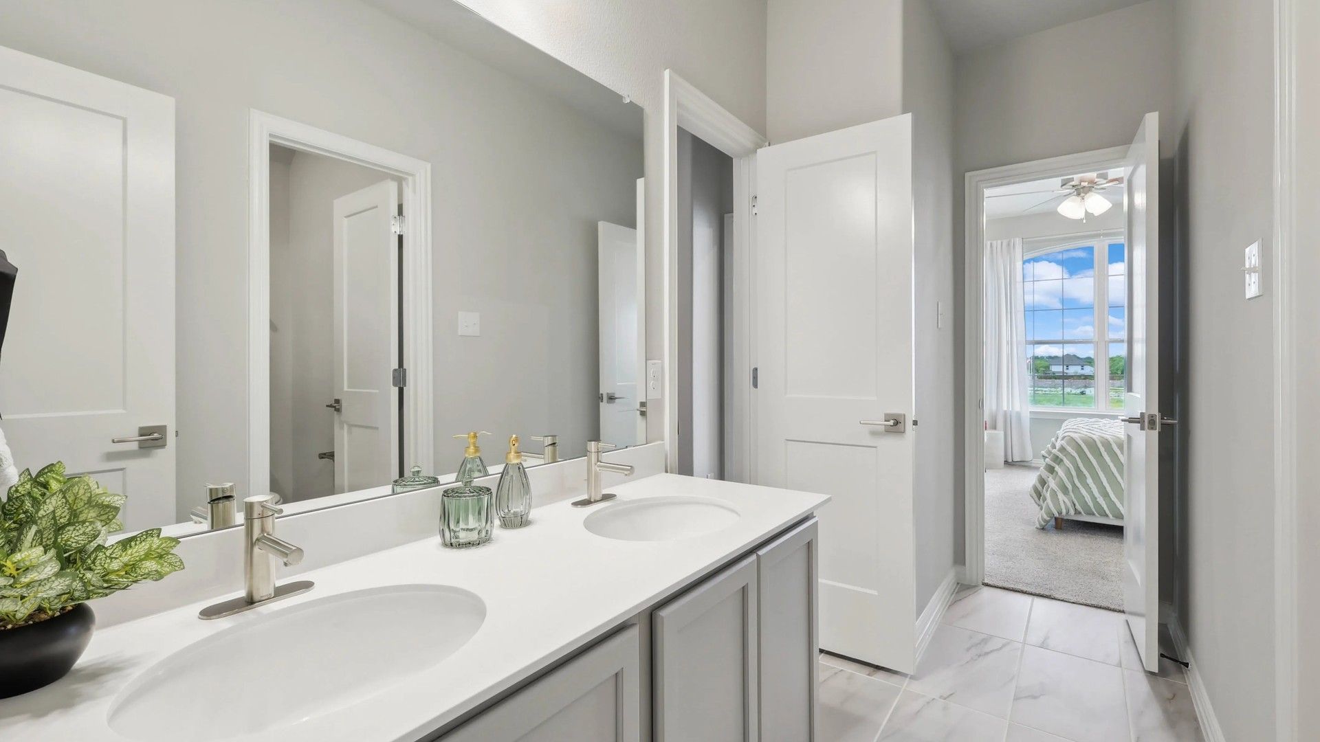 Luxurious double vanity with sleek fixtures and marble flooring in Hulen Trails.