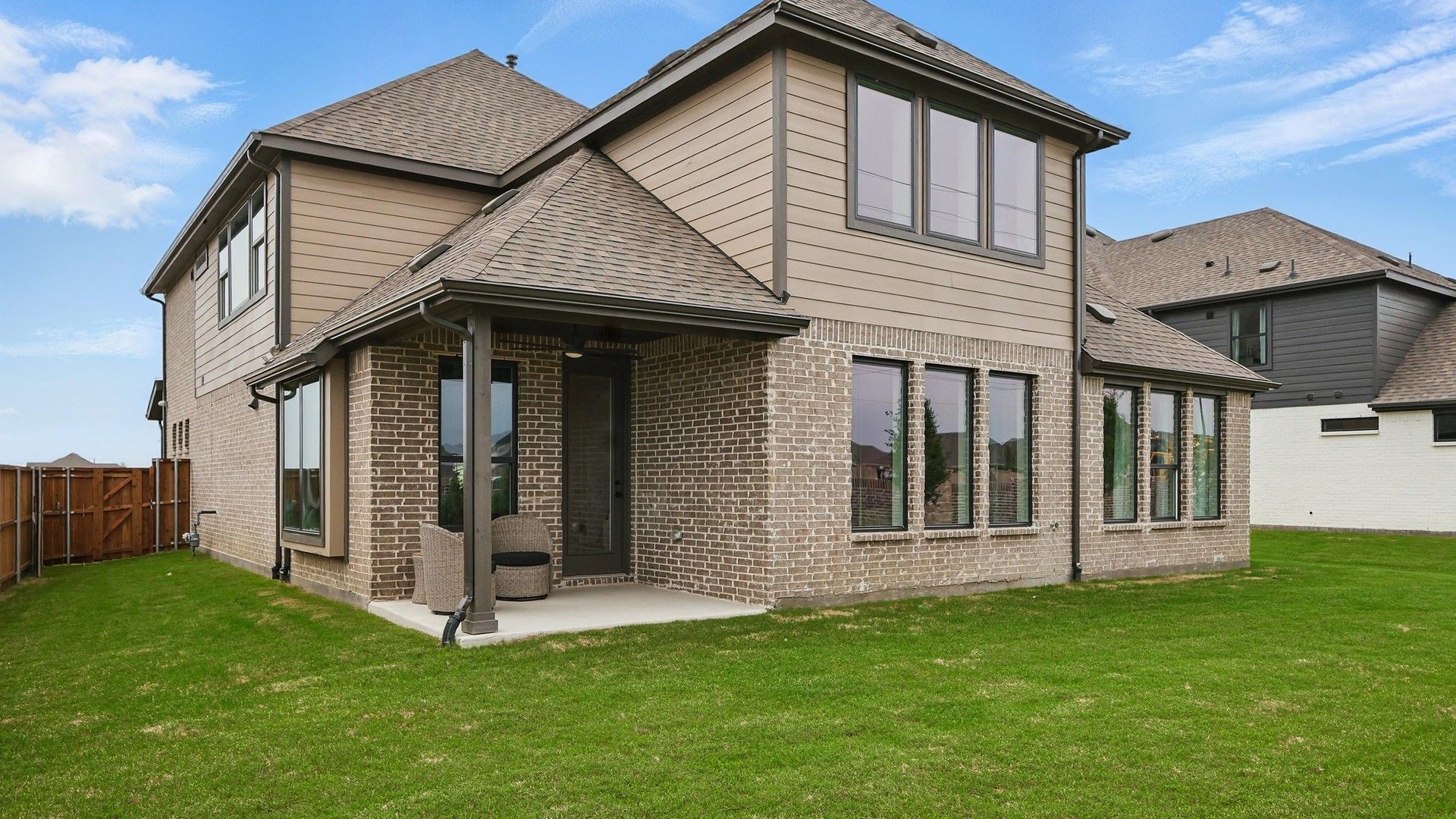 Elegant brick facade with expansive windows in Westridge showcases luxury living with a spacious backyard.