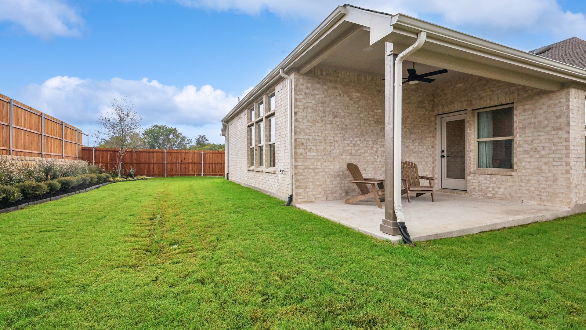Elegant patio with brick facade and expansive lawn in Churchill. Modern fencing enhances privacy.