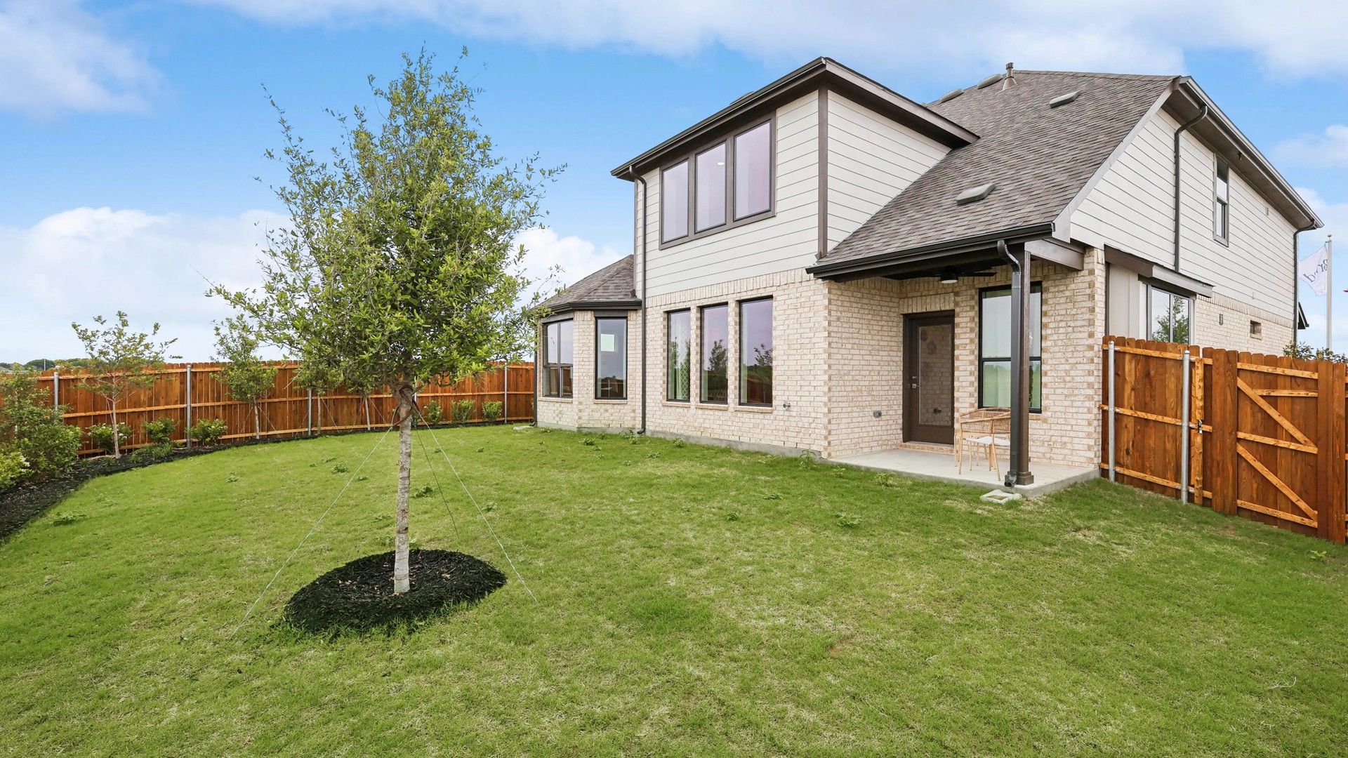 Elegant two-story brick residence with expansive windows and lush lawn in Hulen Trails.