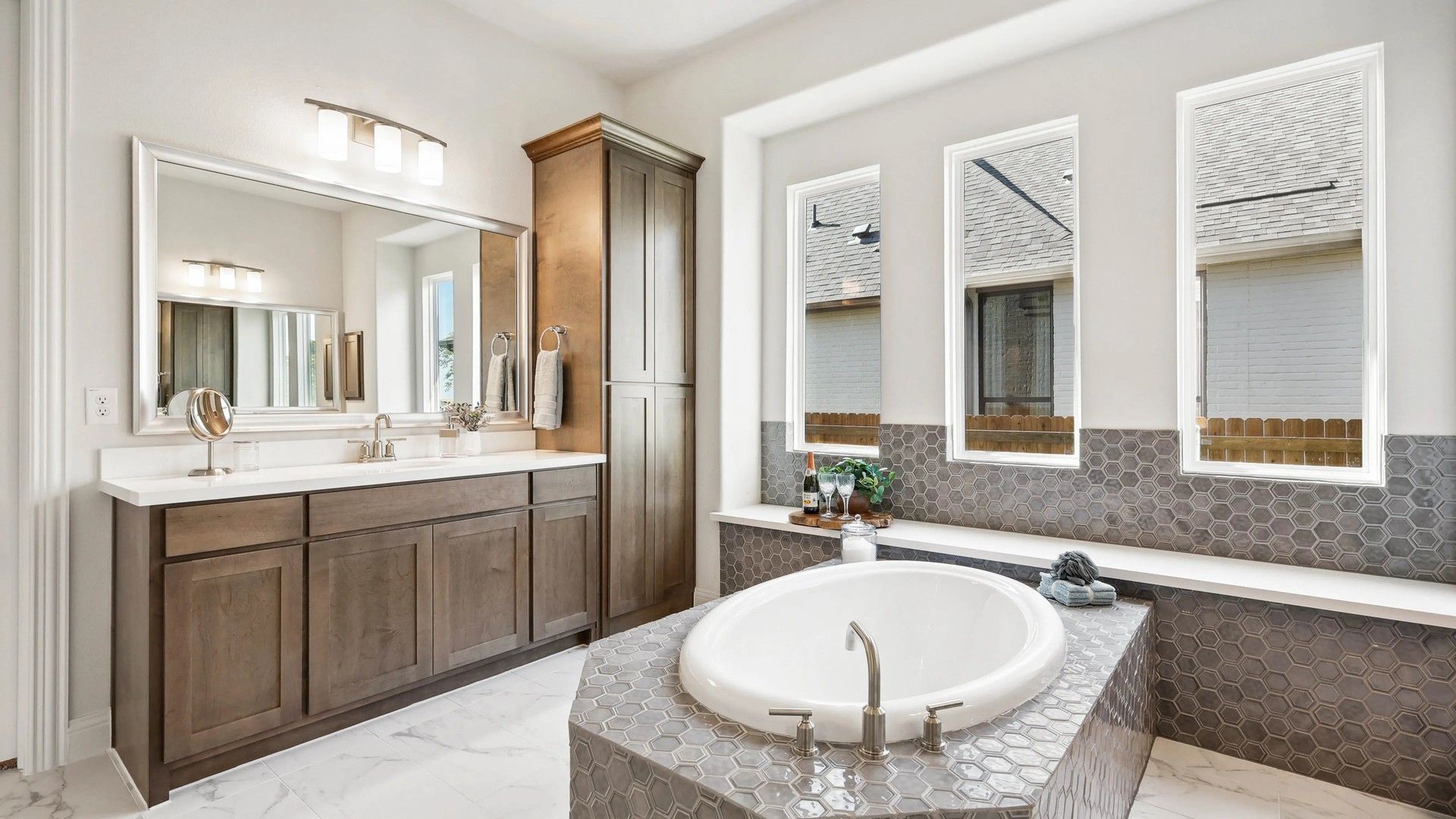 Experience elegance with hexagonal tile design, oval bathtub, and premium wooden cabinetry in Ridge Crossing.
