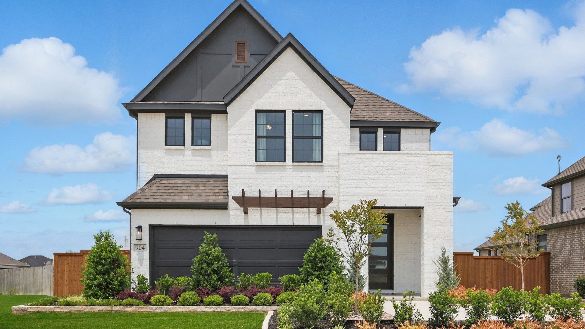 Elegant white brick facade with striking black trim in Westridge. Beautifully landscaped with vibrant greenery.