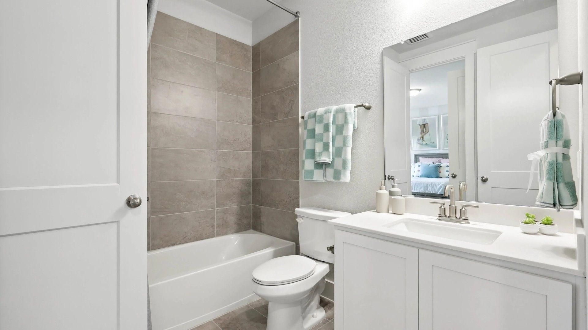 Elegant bathroom with sleek tile work, pristine white vanity, and polished fixtures in Collin Creek.