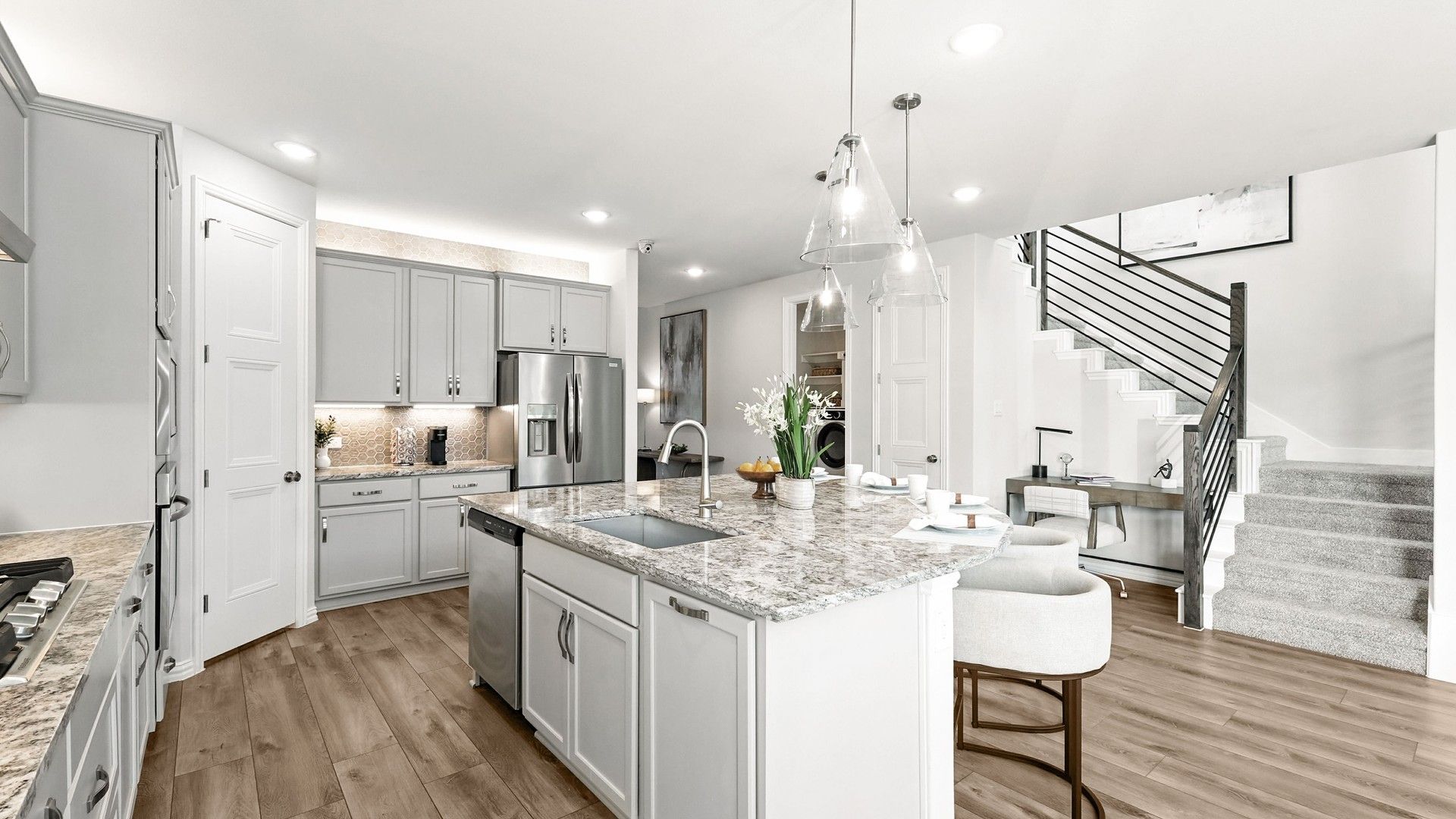 Exquisite marble island and sleek pendant lighting enhance this Green Oaks Preserve kitchen.