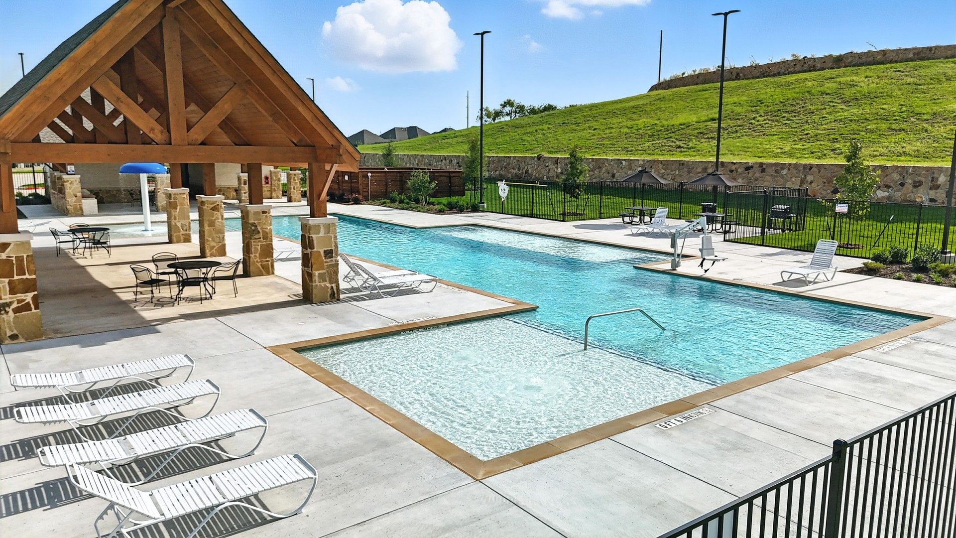 Experience luxury with this expansive pool and elegant wooden pavilion, framed by stone pillars, at Westside Preserve.