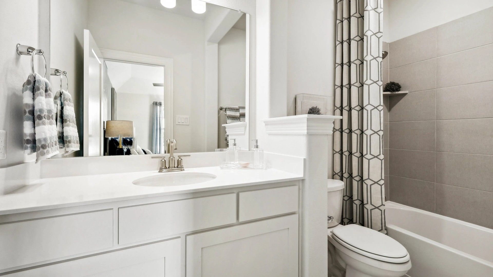 Elegant white vanity and chic geometric shower curtain in a Ridge Crossing residence.