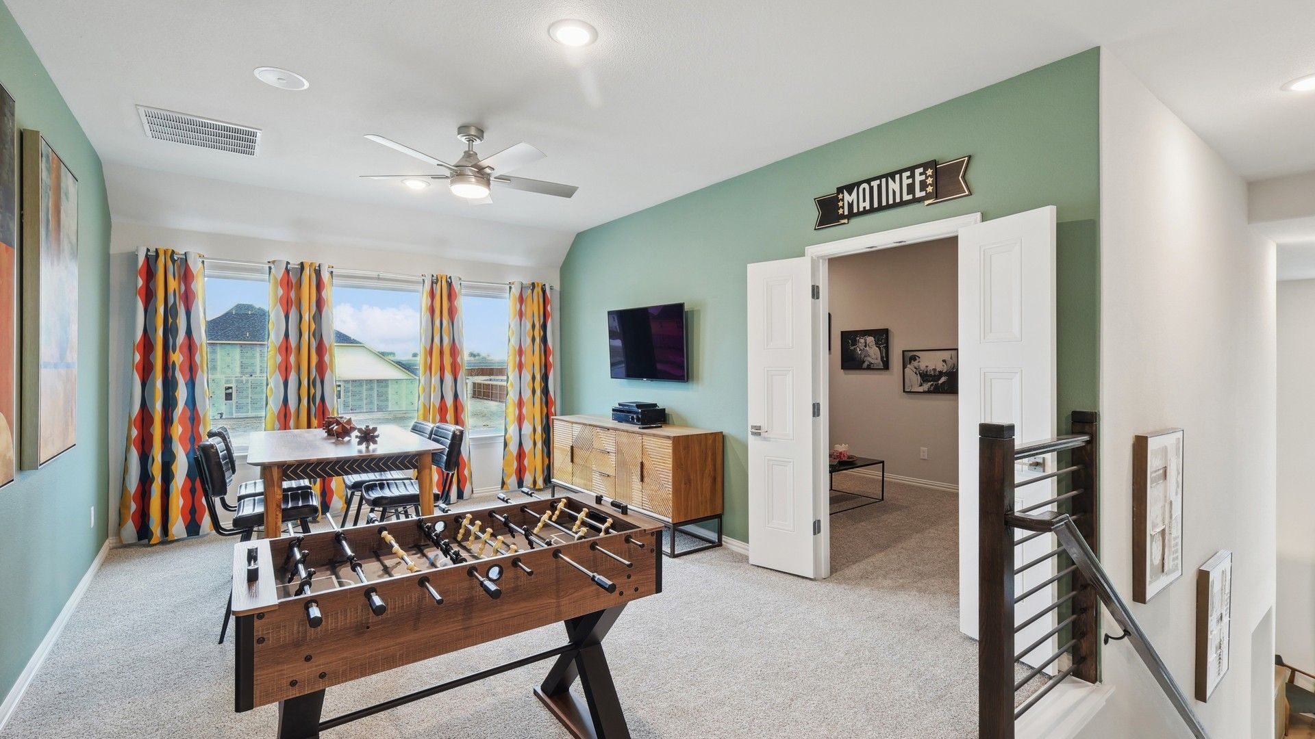 Elegant game room features sleek foosball, vibrant curtains, refined finishes. Wildflower Ranch.