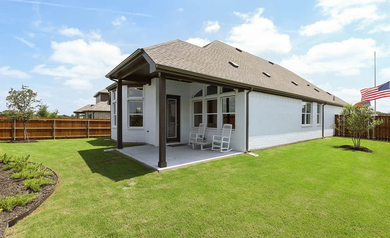 Elegant white brick exteriors with a cozy porch and lush lawn create charm at Thompson Farms.