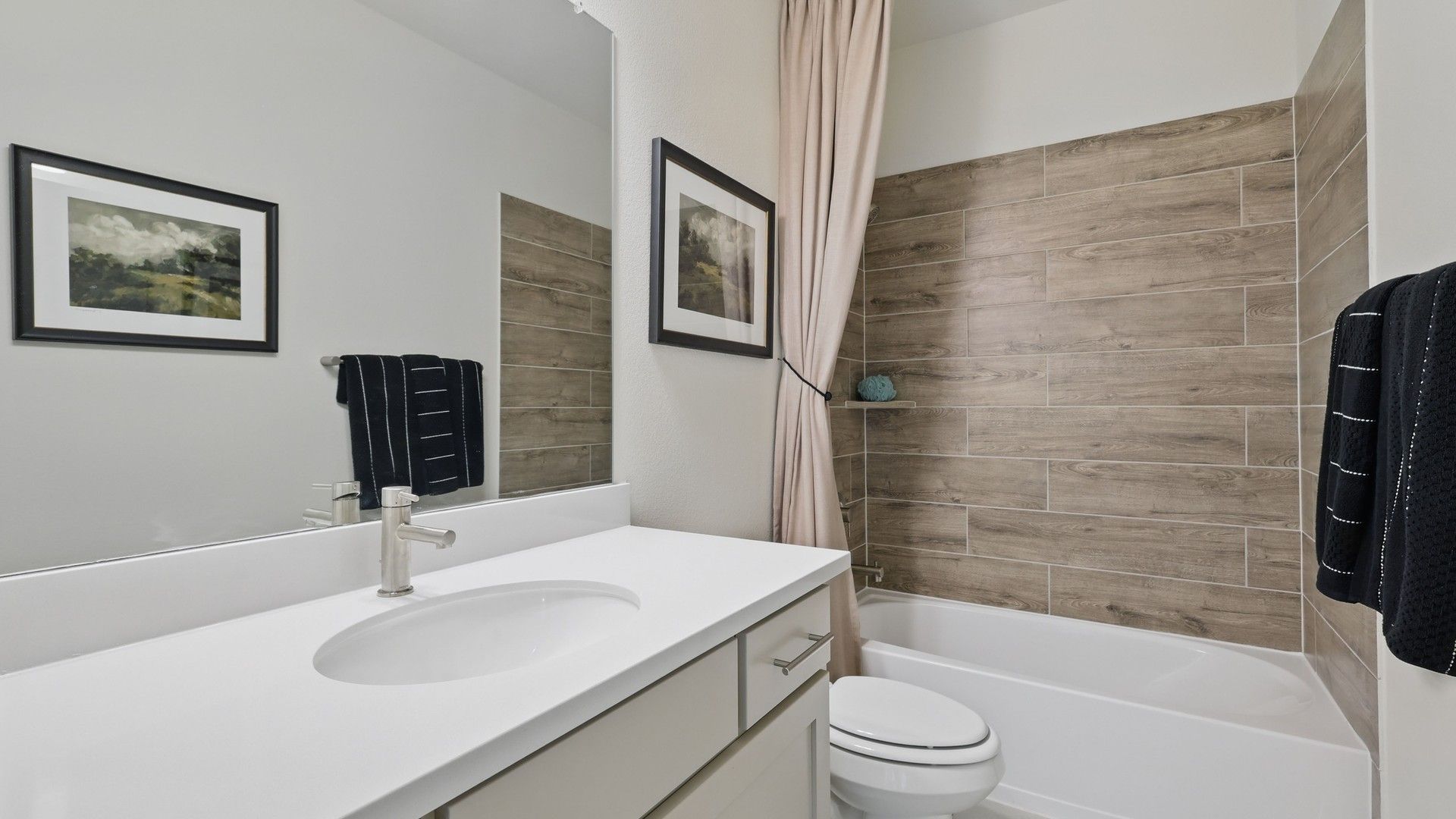 Step into sophistication with sleek wood-patterned tiles and a pristine vanity in Kelly Ranch.