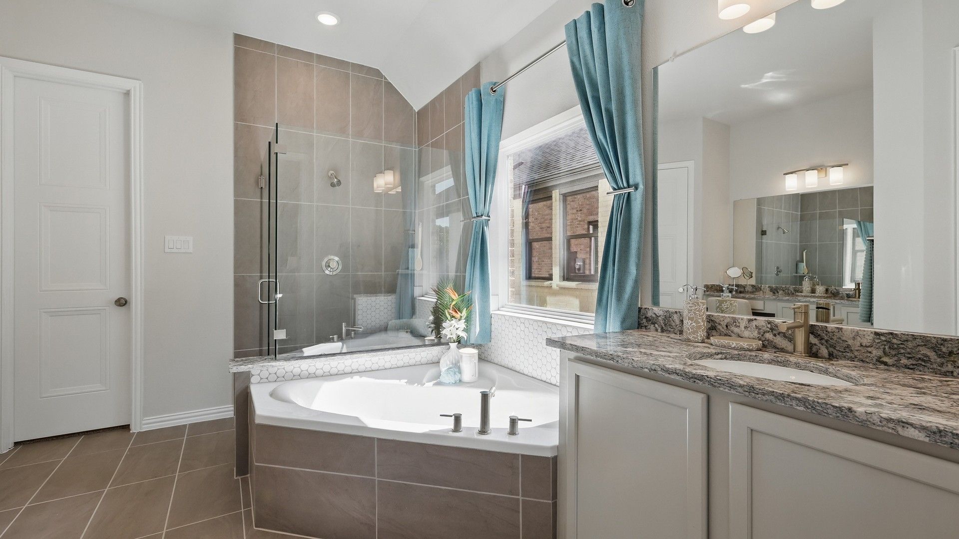 Elegant tub, glass shower, and granite counter enhance this Green Oaks Preserve bathroom's opulence.