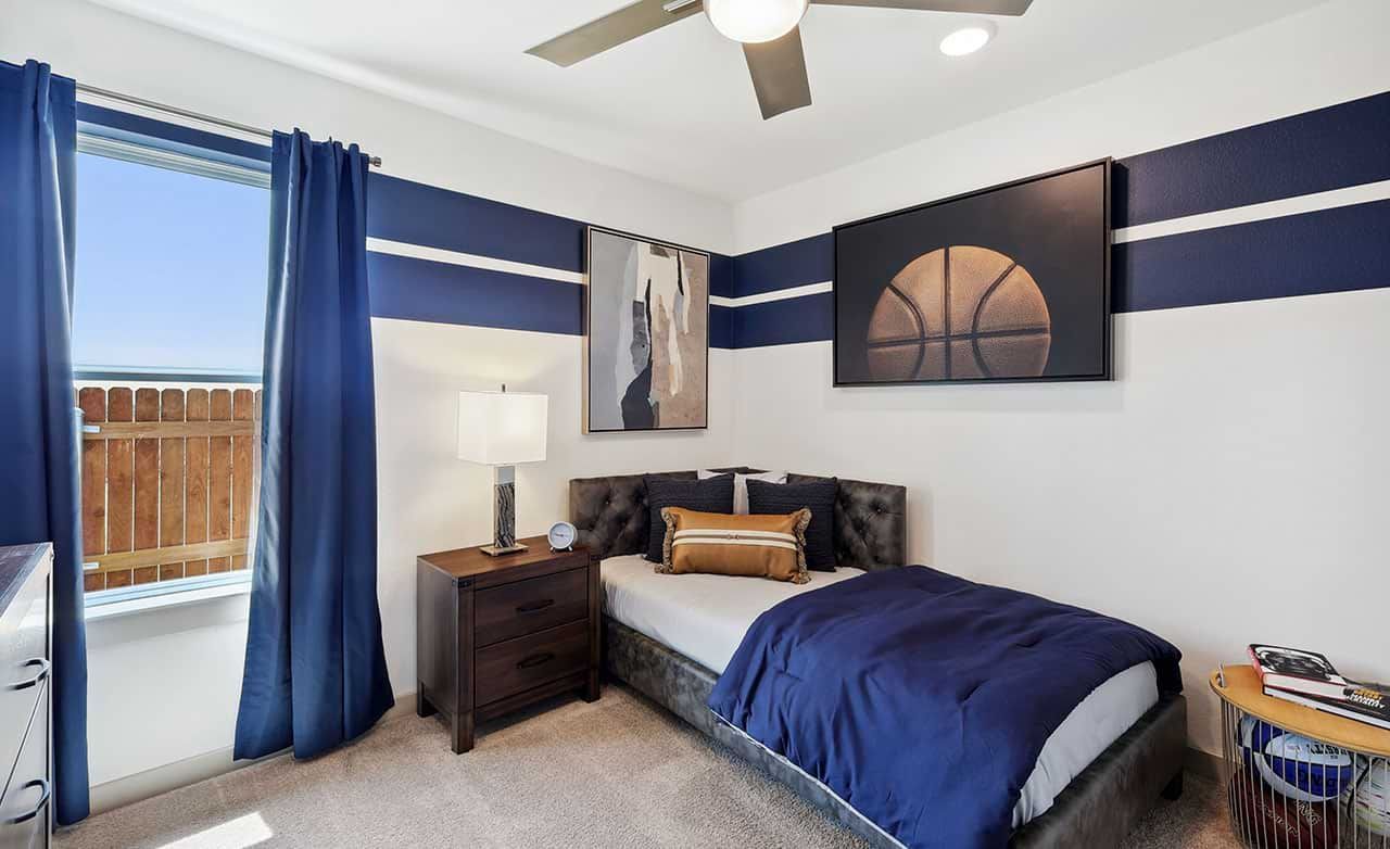 Elegant tufted bed against navy stripes, refined artwork, and seamless lighting in Walden Pond's stylish setting.
