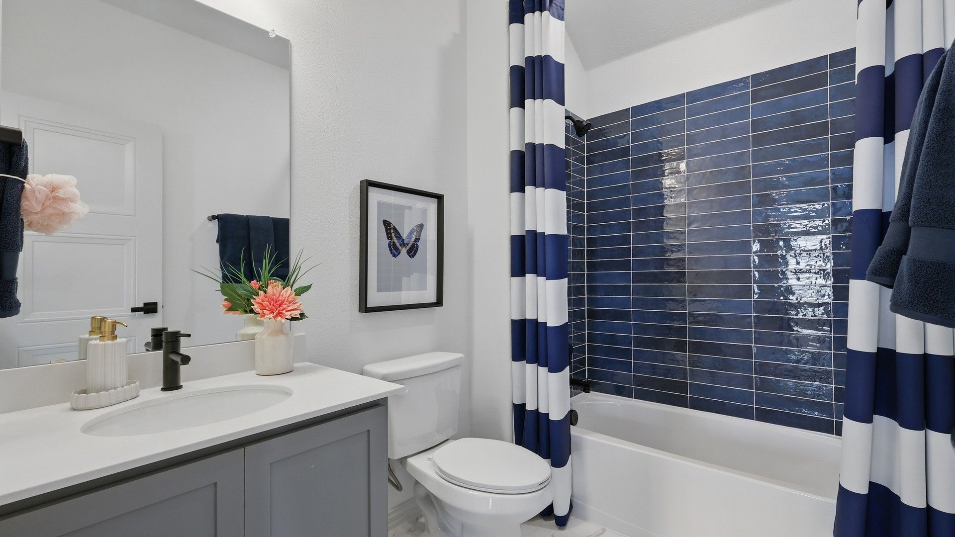Luxurious Westridge bathroom features navy tiles, chic striped curtains, and a sleek modern vanity.