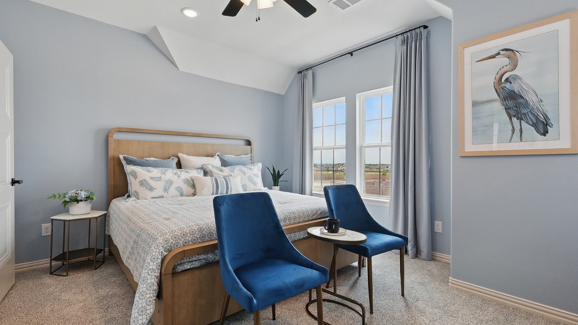 Luxurious Westridge bedroom features velvet chairs, a chic wooden bed, and captivating heron artwork.
