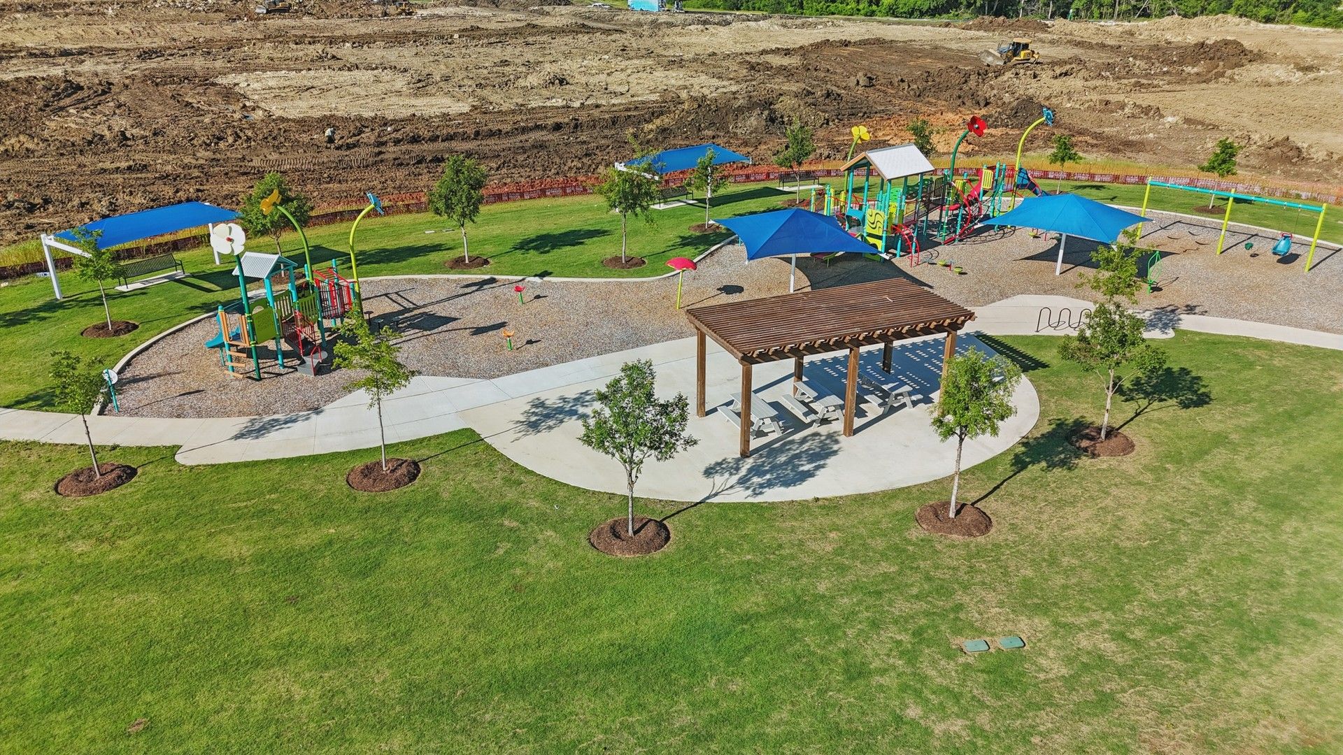 Vibrant playground with shaded areas and lush green lawn in Wildflower Ranch offers premium outdoor leisure.