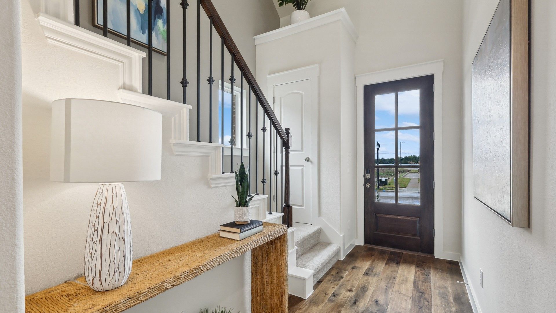 Luxurious Churchill entryway boasts rich wood floors, white stairway with wrought iron, and natural light.