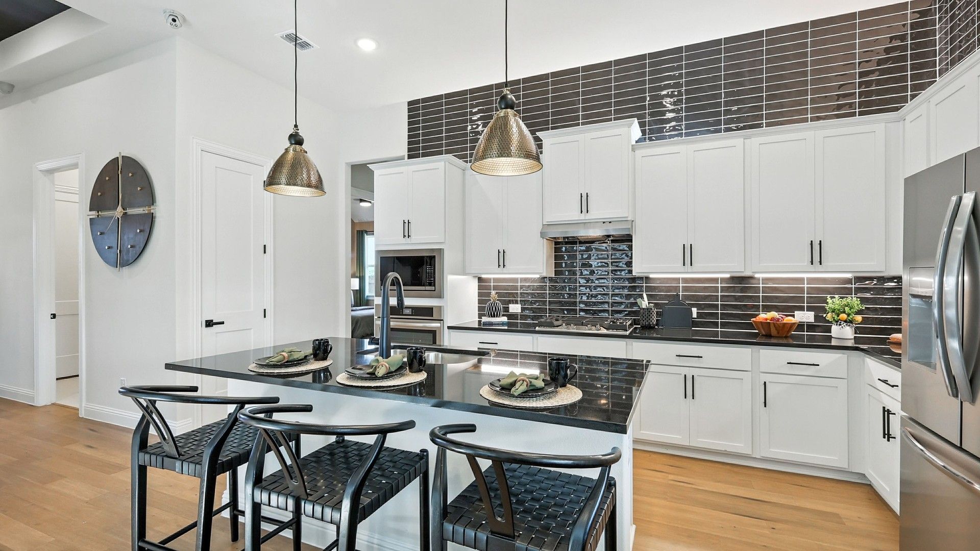 Sleek white cabinetry and glossy black tiles define this exquisite kitchen in Green Oaks Preserve.
