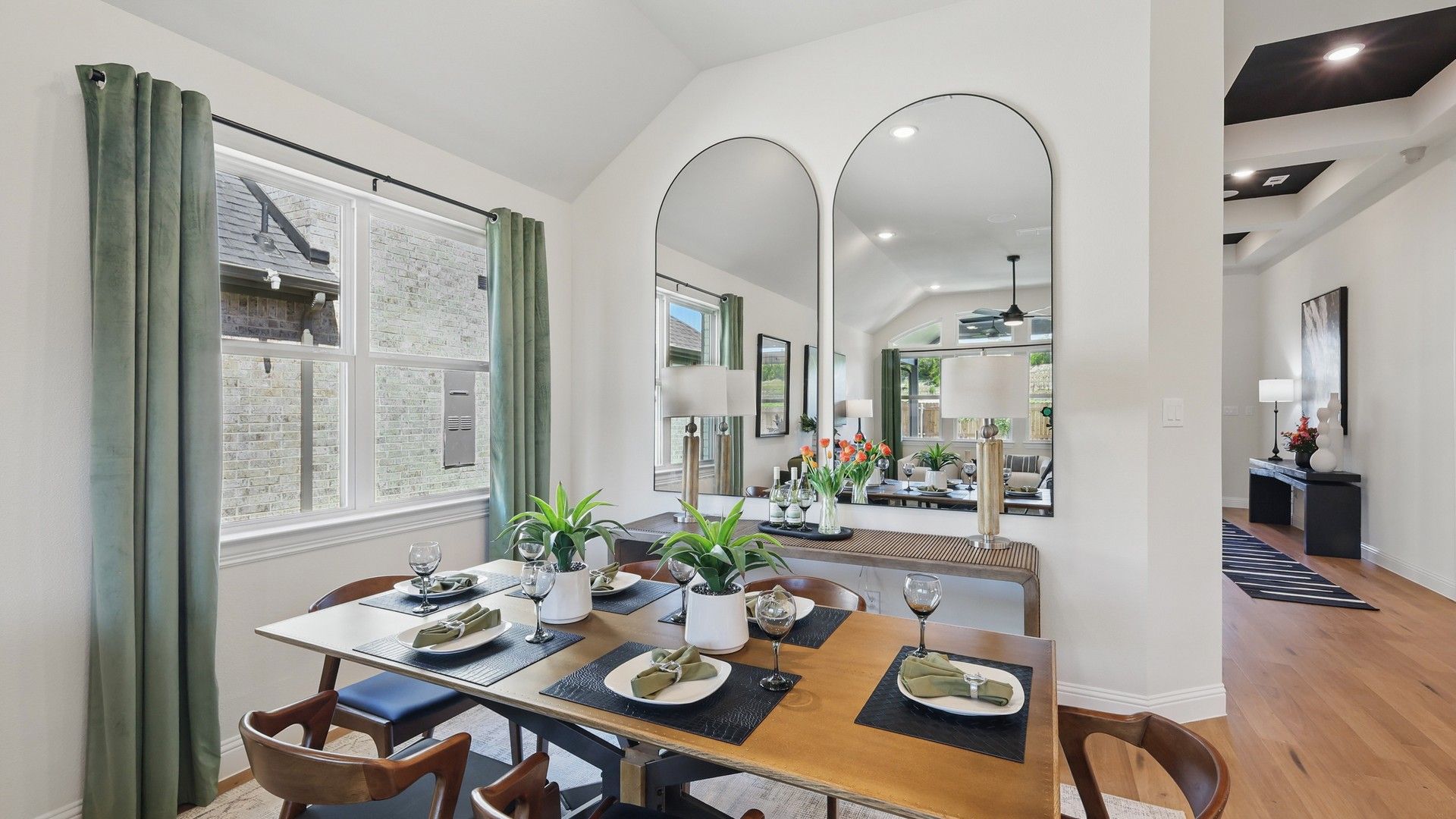 Luxurious dining room with vaulted ceiling and expansive mirrors in Green Oaks Preserve community.