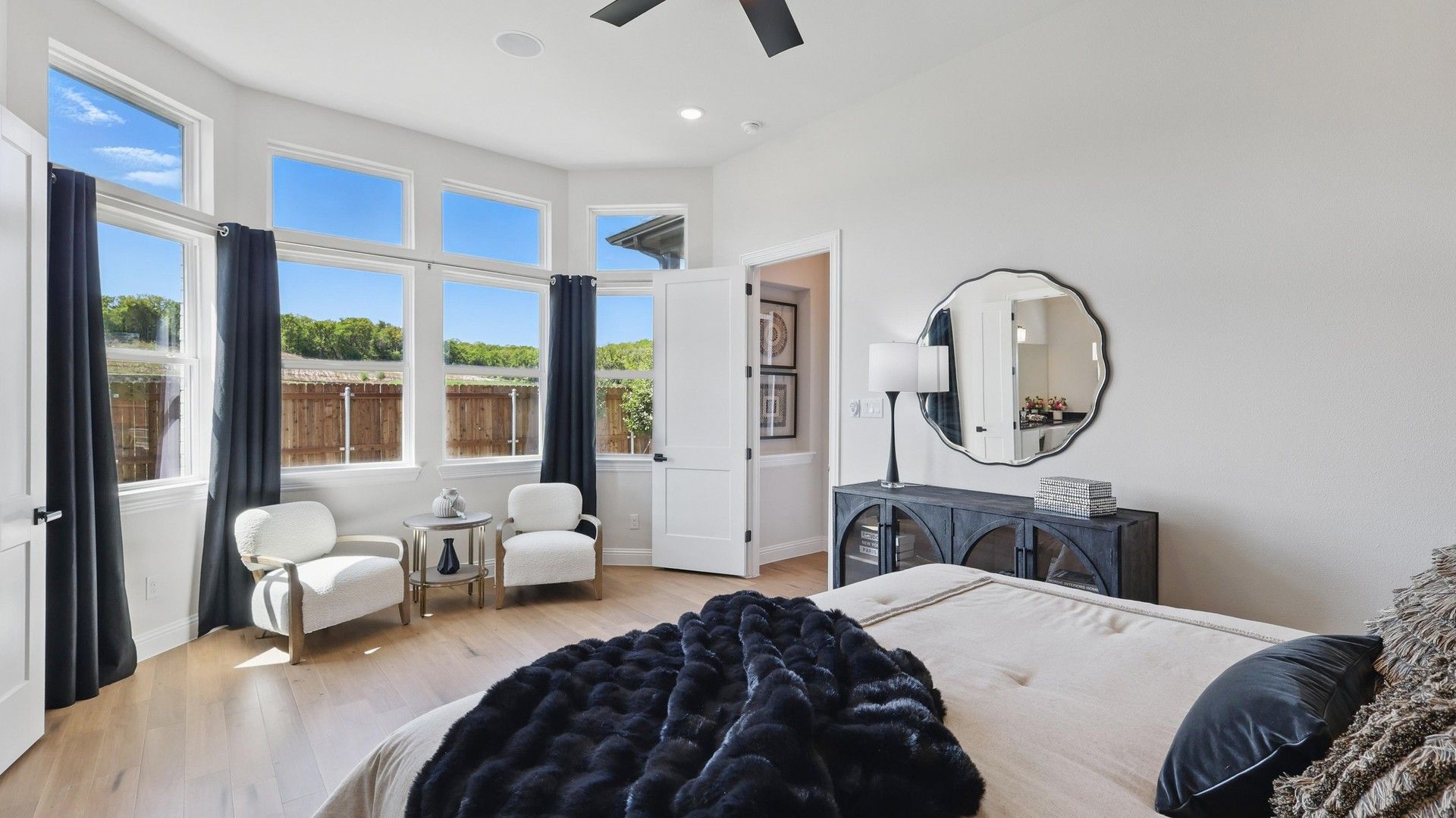 Expansive windows illuminate sleek hardwood floors and elegant decor in Green Oaks Preserve's serene bedroom.