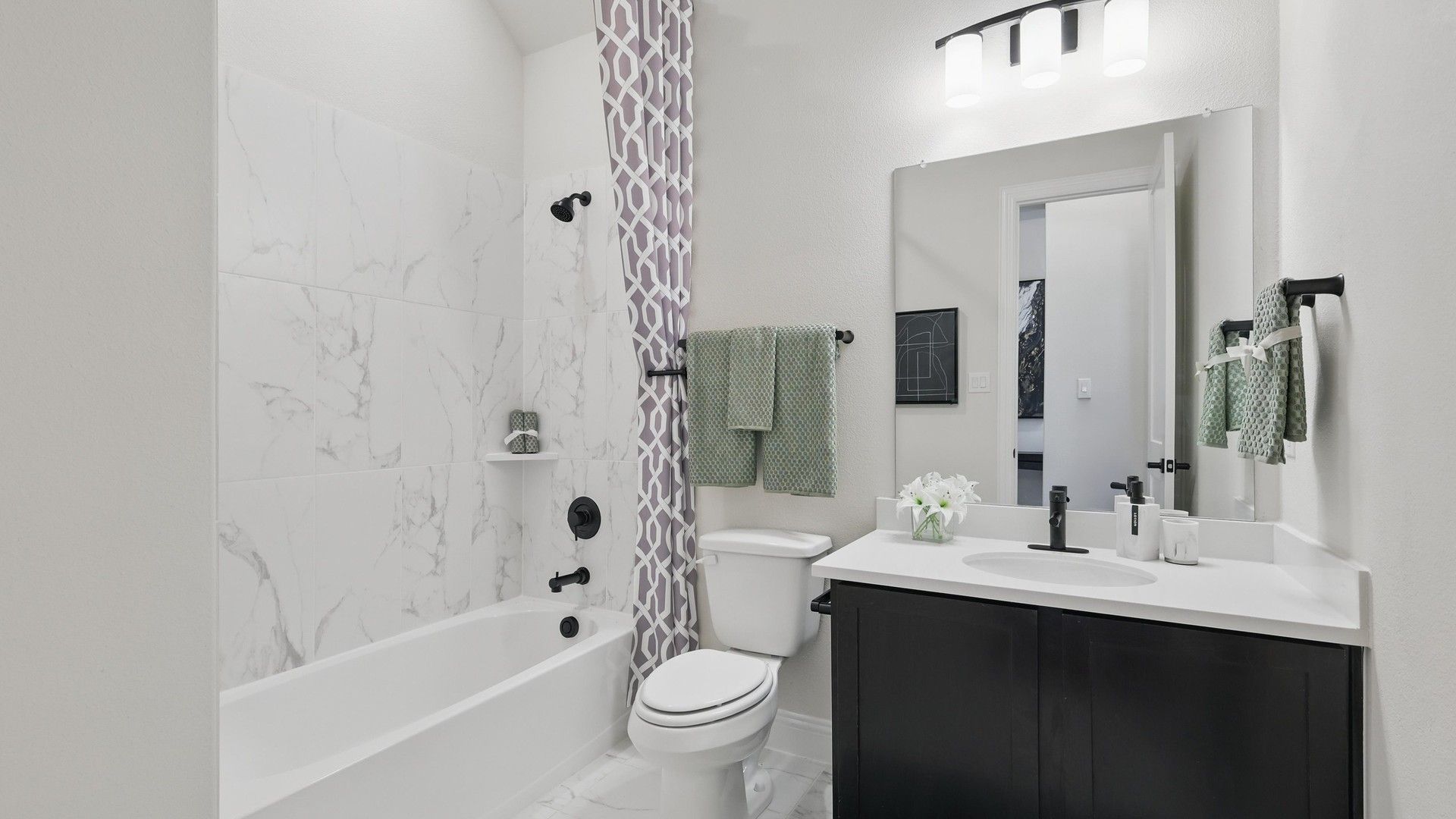 Indulge in elegance with marble tile features and sleek black fixtures in this Green Oaks Preserve bathroom.