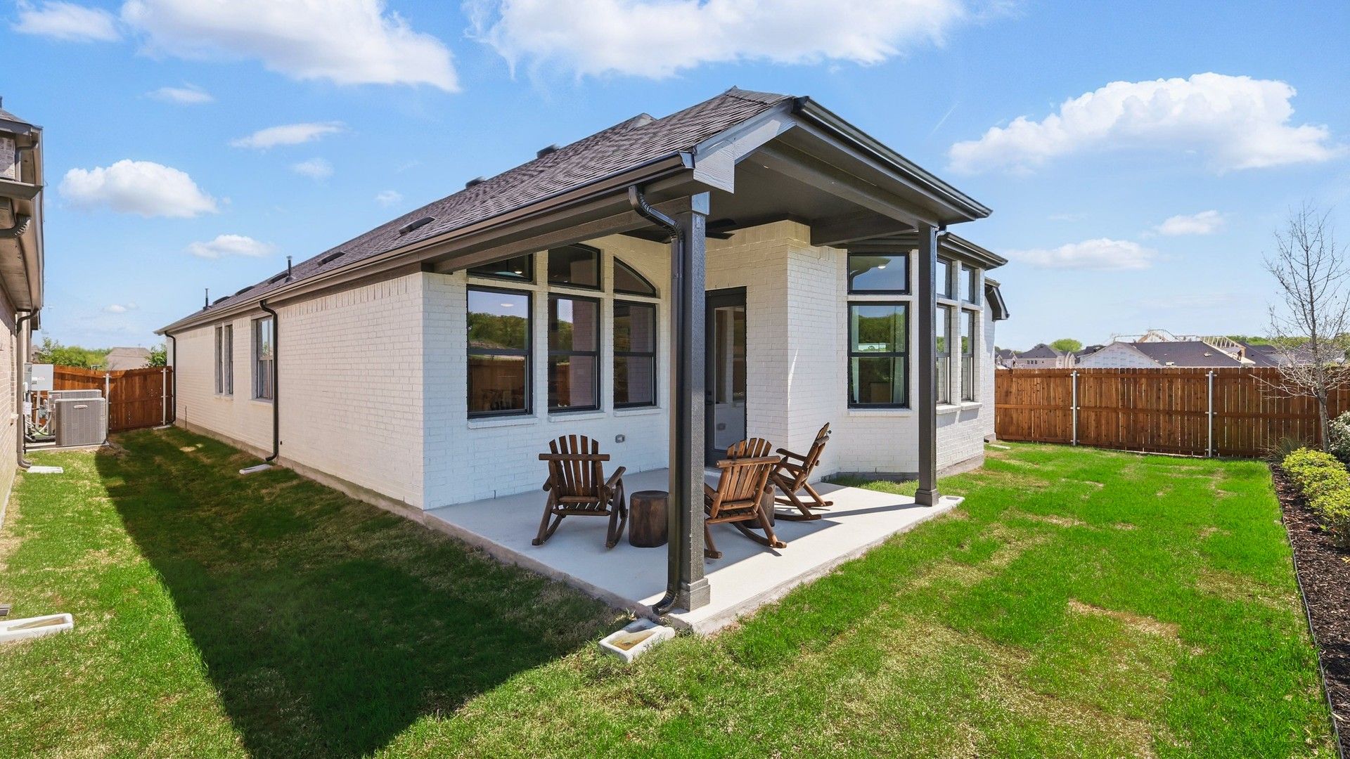 Luxurious white brick facade with spacious patio, elegant gable roof; Green Oaks Preserve.