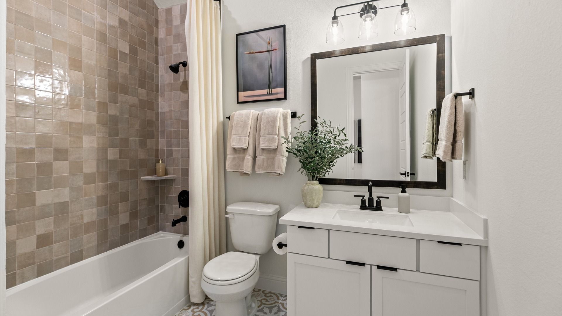 This secondary bath showcases eye-catching multi-tone tiling complemented by crisp white cabinetry and counters.