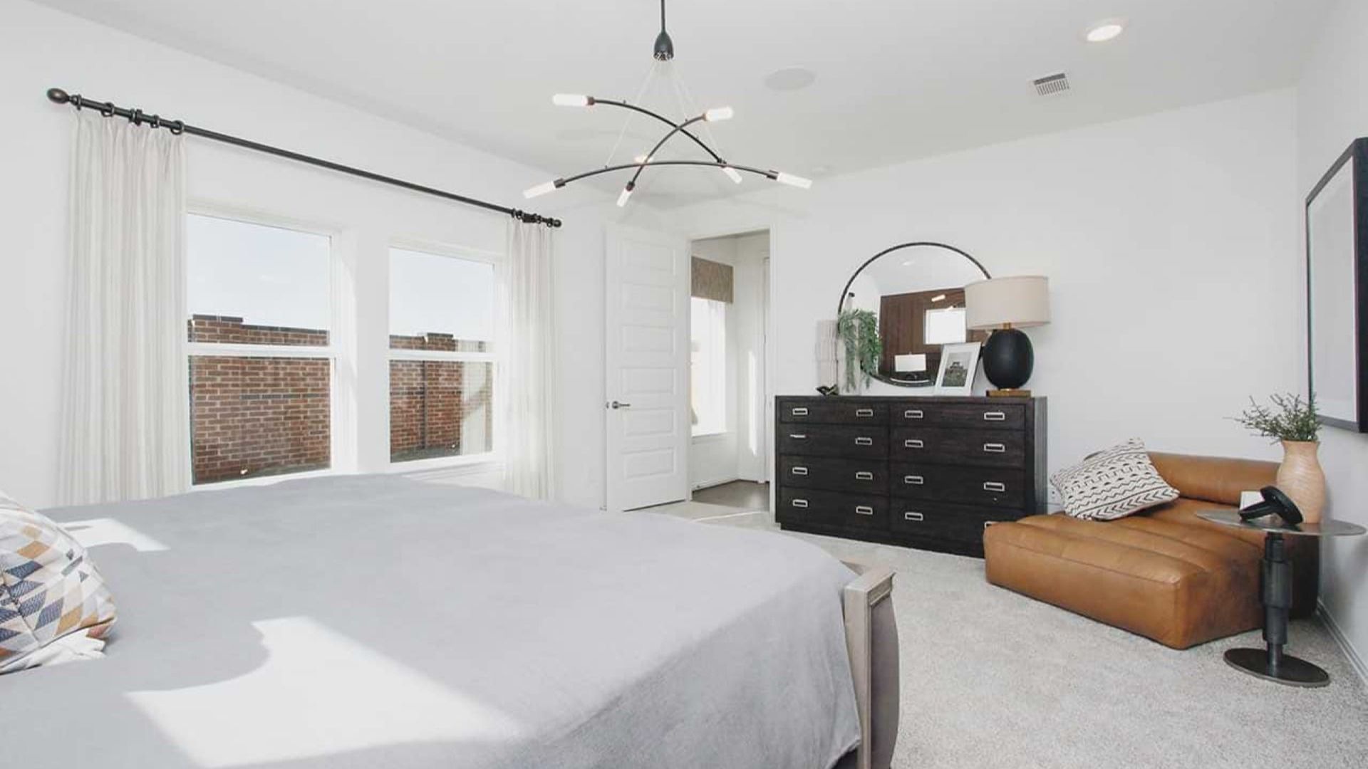 Elegant bedroom with modern lighting fixtures and plush textiles in Cypress Green community.