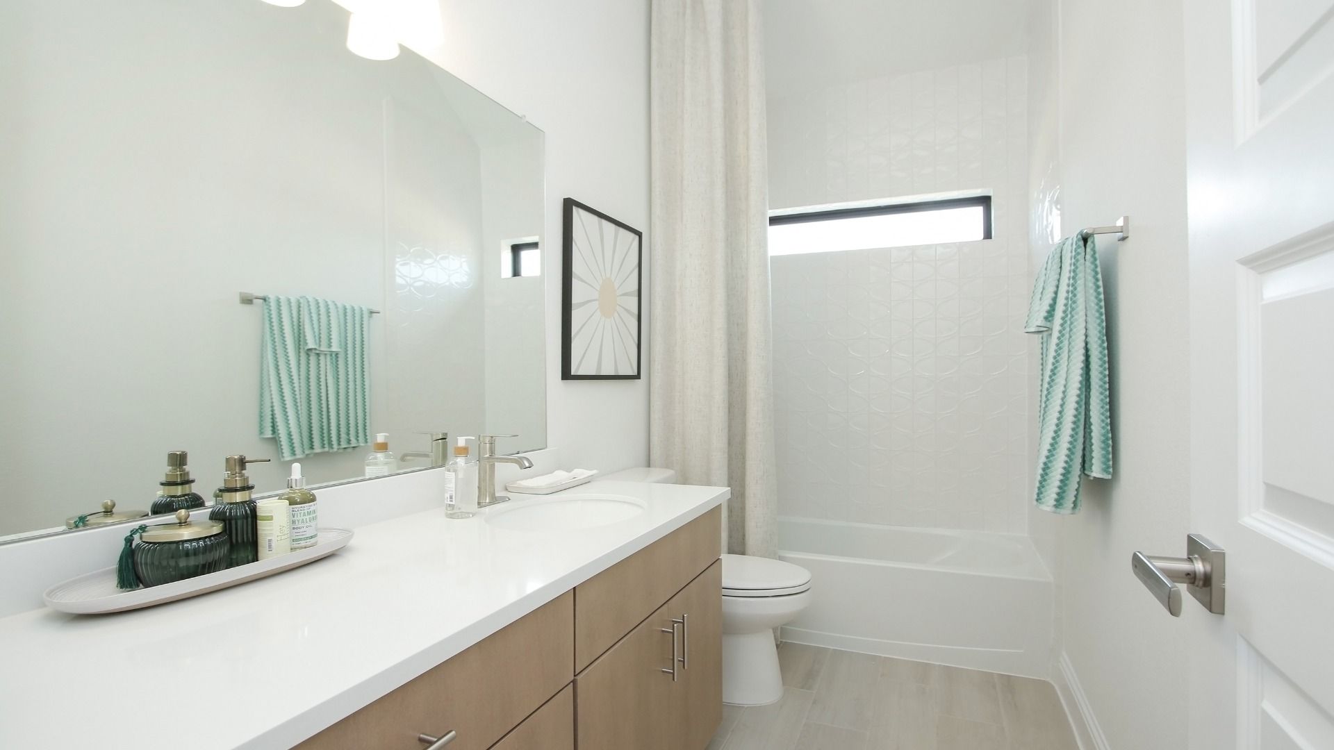 Sleek bathroom features modern vanity, luxurious tiling, and refined finishes in Sunterra community.