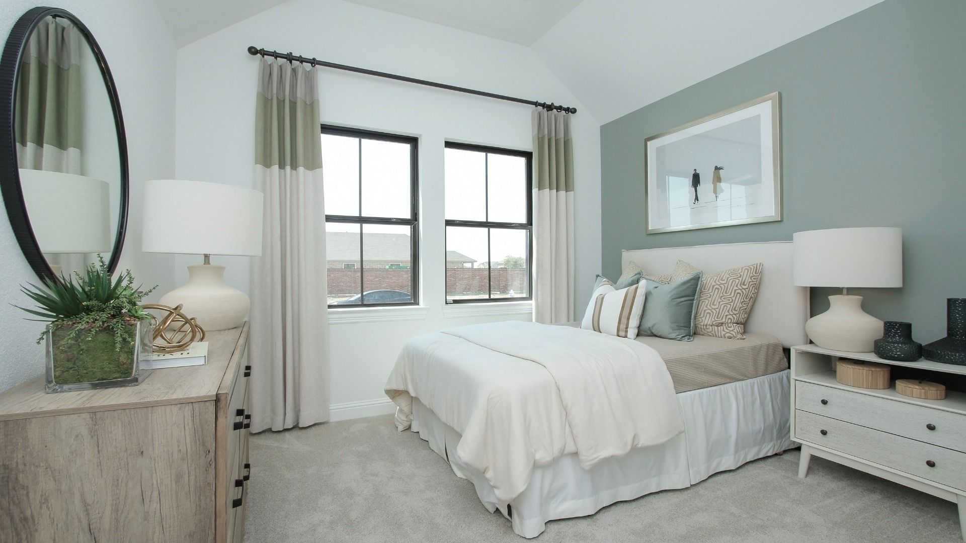 Sunterra bedroom boasts vaulted ceilings, elegant pale green accent wall, and expansive windows for airy luxury.