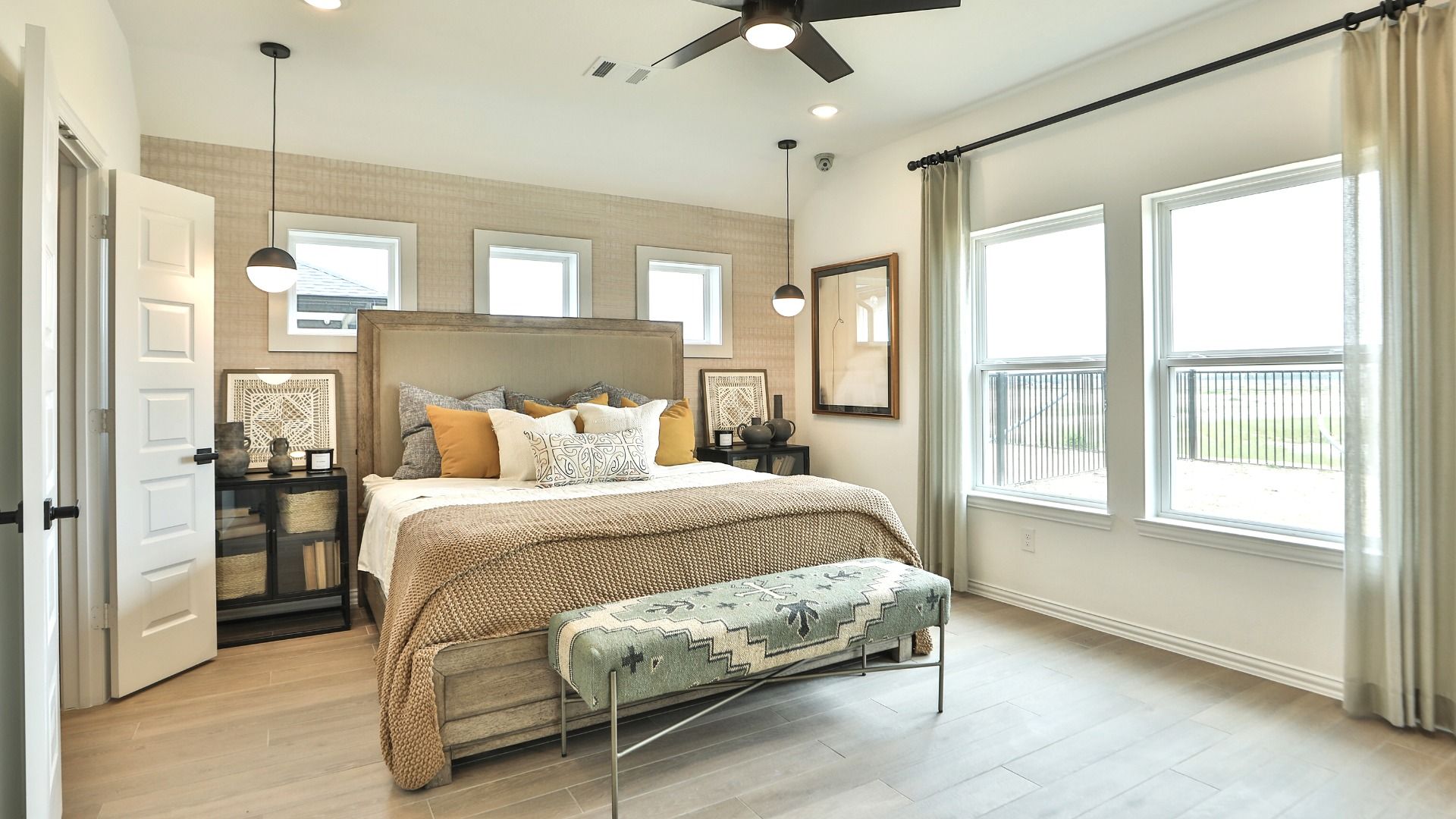 Exquisite modern bedroom with large windows, sleek ceiling fan, and plush furnishings in Bridgeland.
