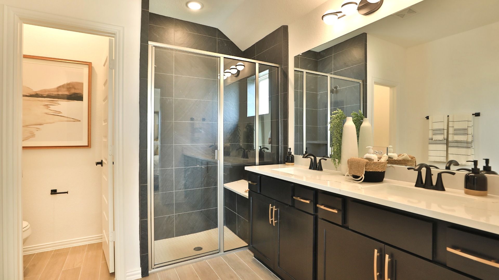 Bridgeland bath boasts exquisite glass shower, chic dark cabinetry, and refined lighting. Elegant above all.