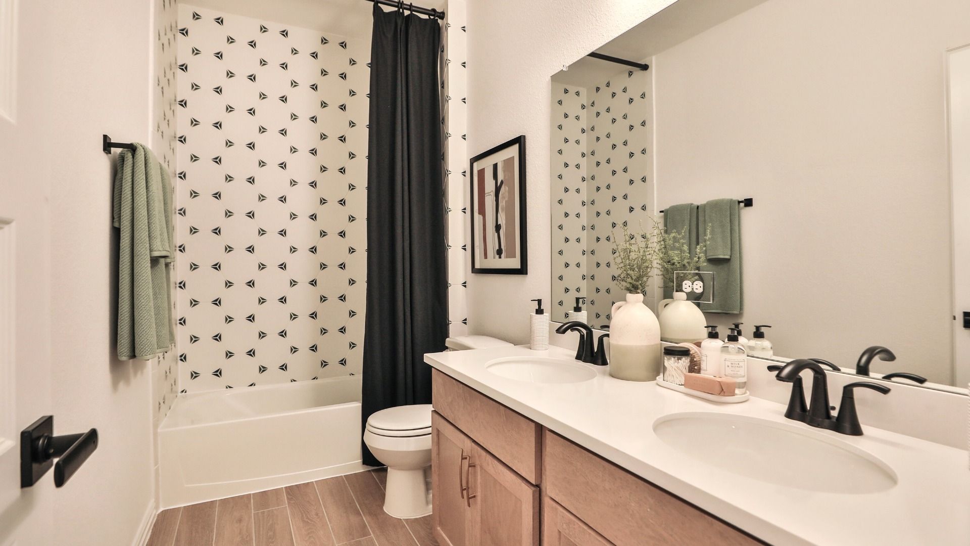 Luxurious Bridgeland bathroom features striking geometric tiles, chic black fixtures, and dual sinks.