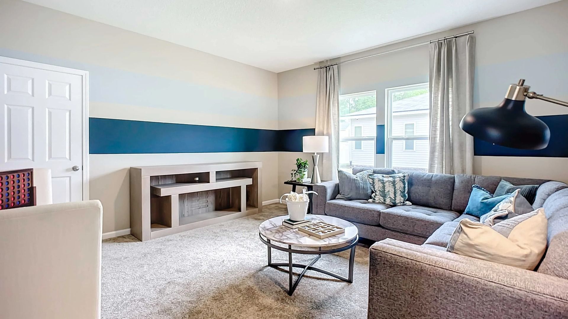 Elegant Panther Creek living room boasts a chic striped accent wall and plush gray sectional.