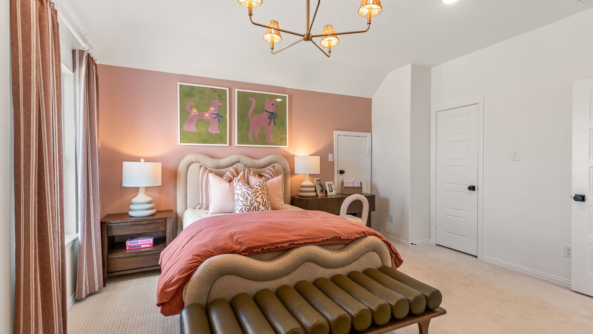 Secondary bedroom with blush pink accent wall and modern lighting.