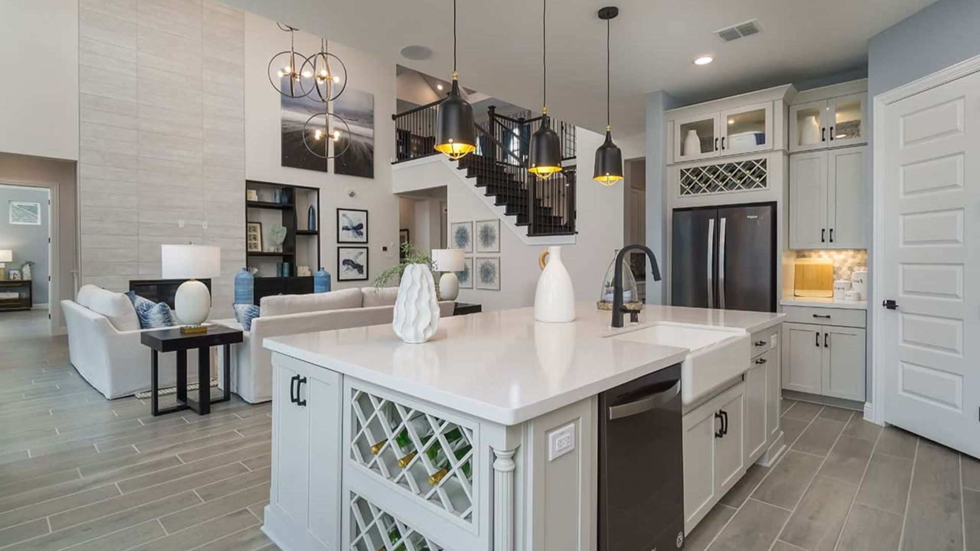 Luxurious kitchen features a sleek white island, sophisticated lighting, and grand staircase at Mostyn Manor Reserve.