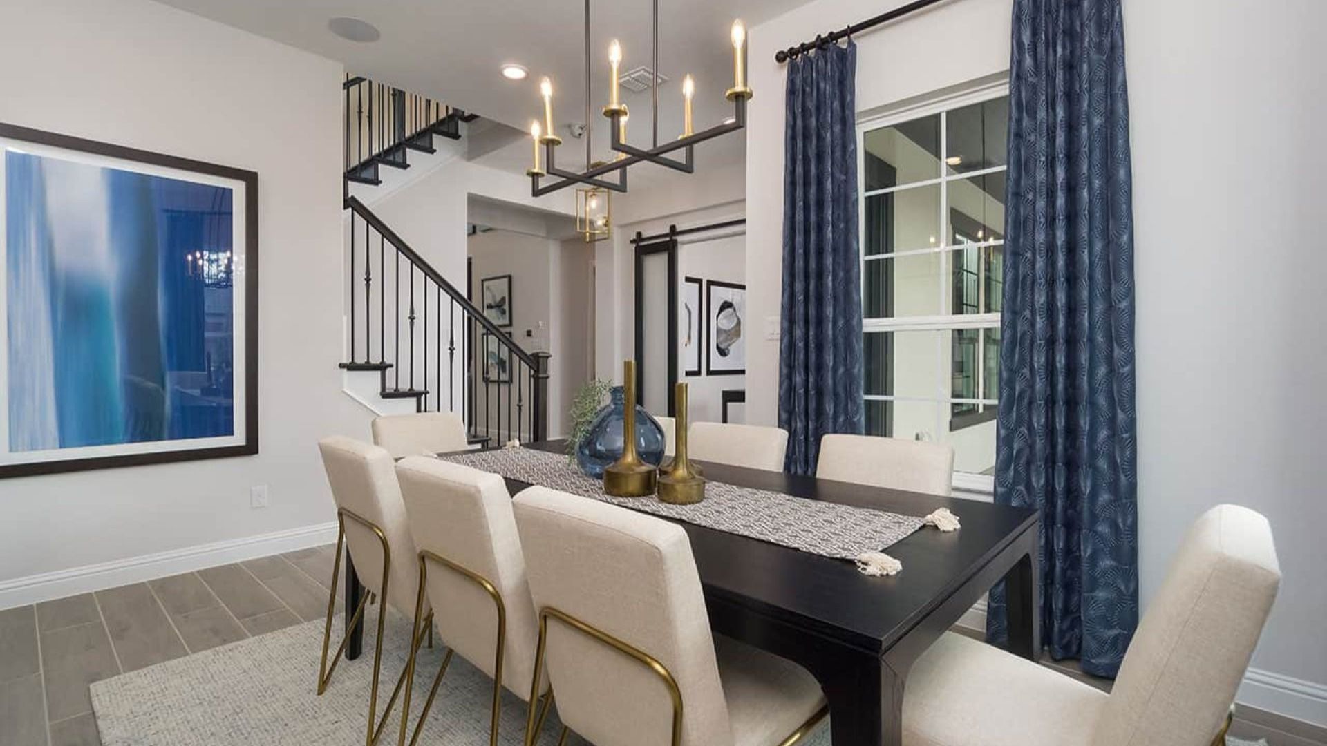 Luxurious dining room features modern chandelier, dark wood table, elegant blue drapery, in Texas estate.