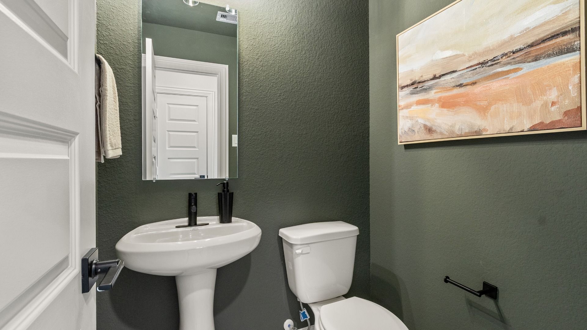 A chic sage green powder room delivers a polished and welcoming touch for visitors.