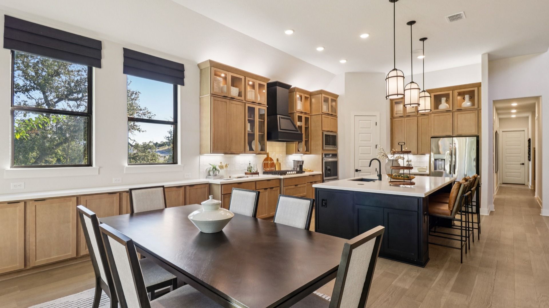 Sunlit dining room features expansive windows, chic shelving, and refined wood finishes. Verandas at the Rim, Texas.