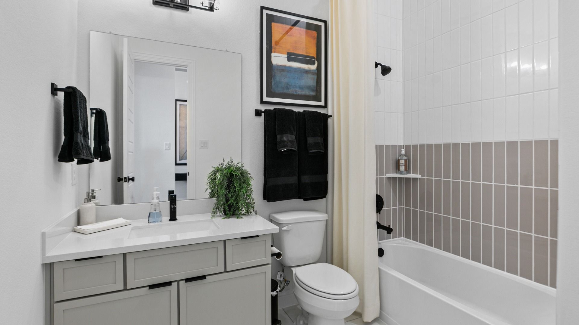 Grey and white tile with matte black finishes creates a clean, modern bathroom in Aldeana.