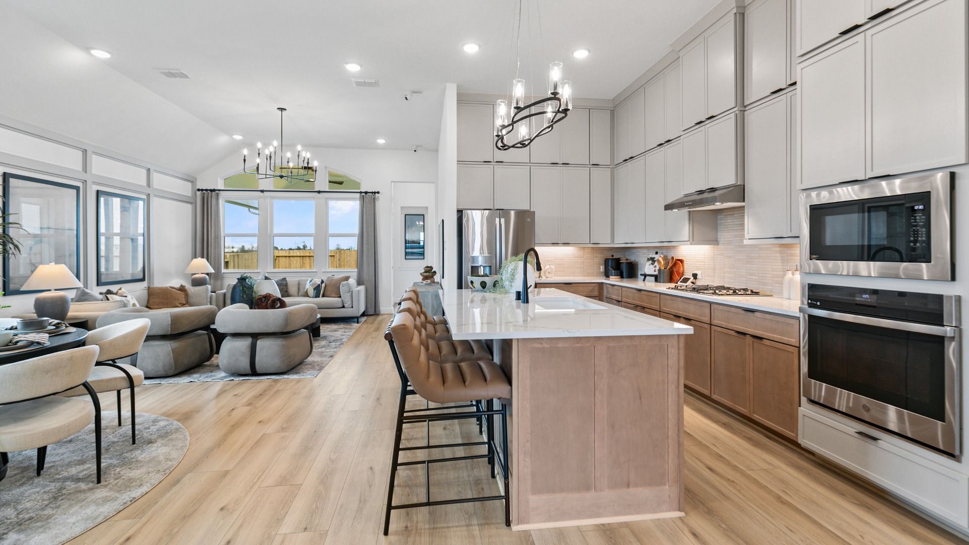 This kitchen in Aldeana features gray upper cabinetry, tan lower cabinetry, and stainless steel appliances.