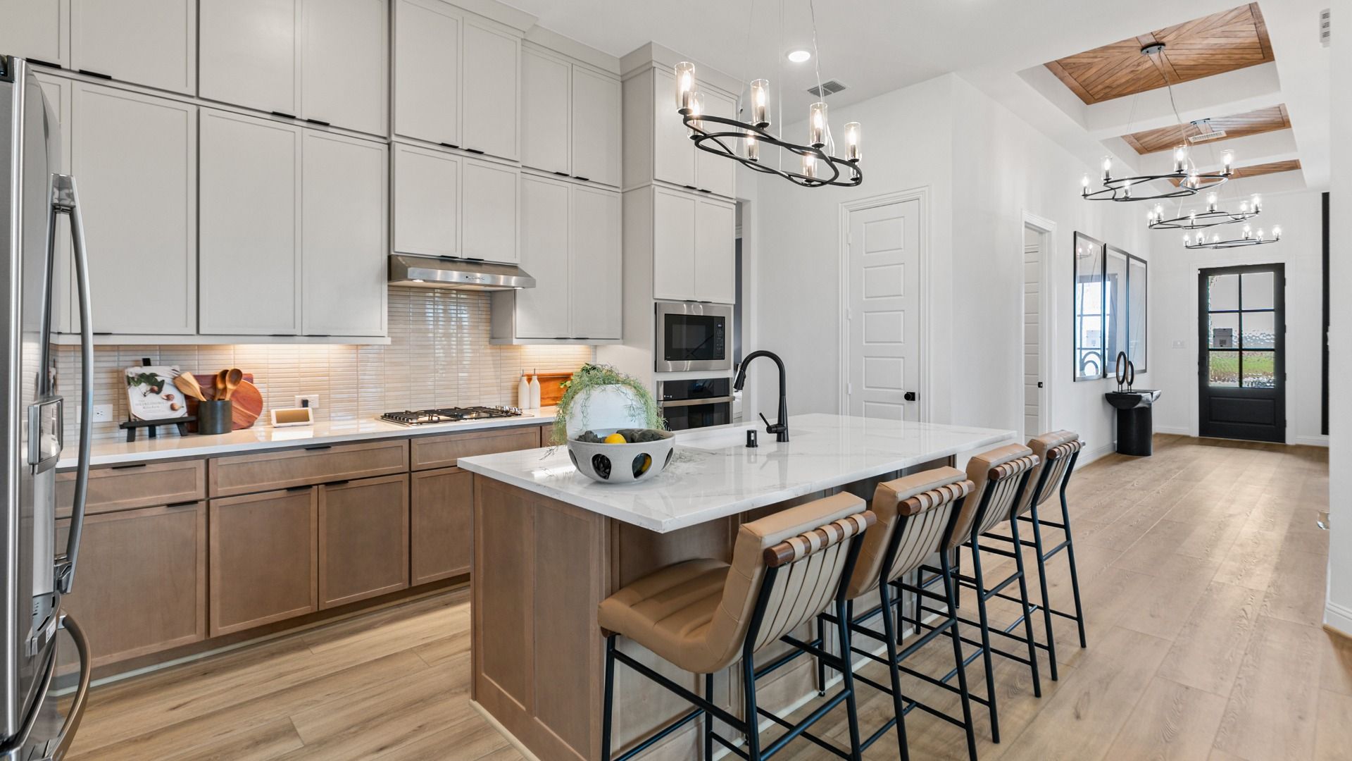 Light tile backsplash highlights this modern kitchen in Aldeana with two-tone cabinetry.
